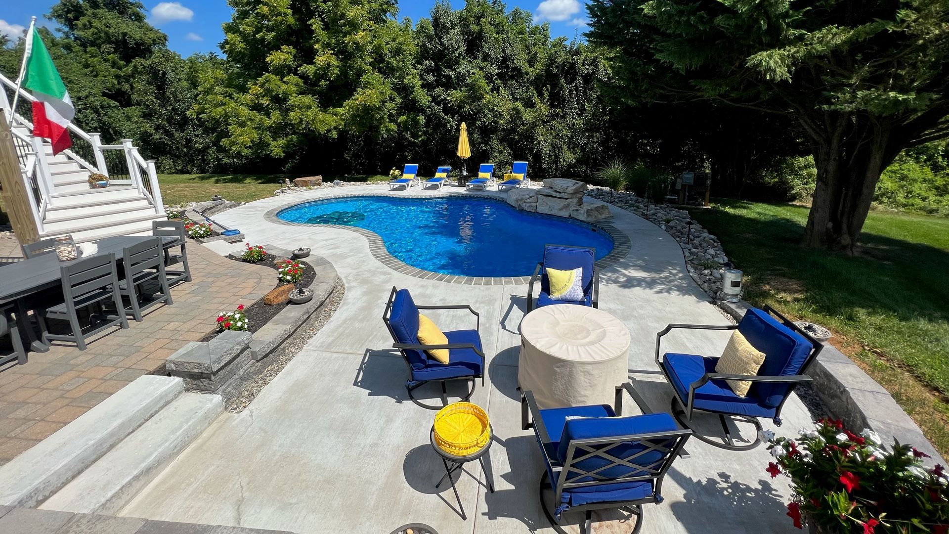 A large swimming pool surrounded by patio furniture and a fire pit.