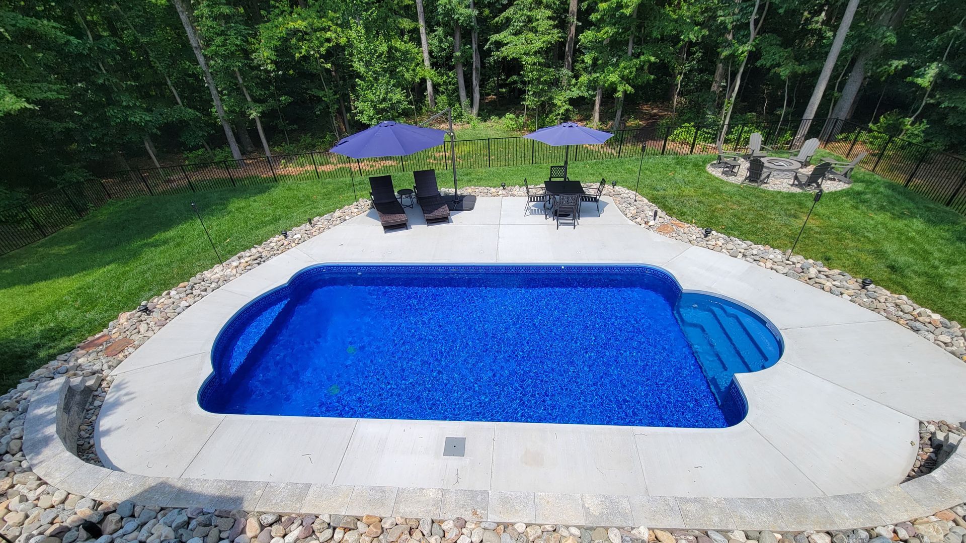 An aerial view of a large swimming pool surrounded by chairs and umbrellas.
