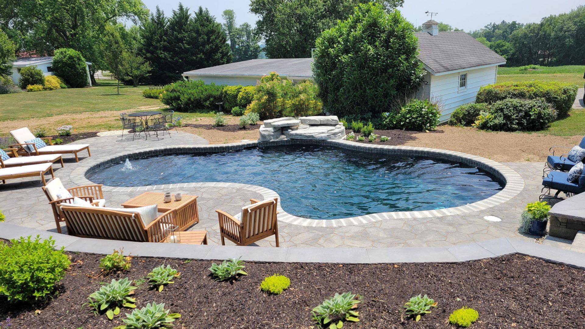 There is a large swimming pool in the backyard of a house.