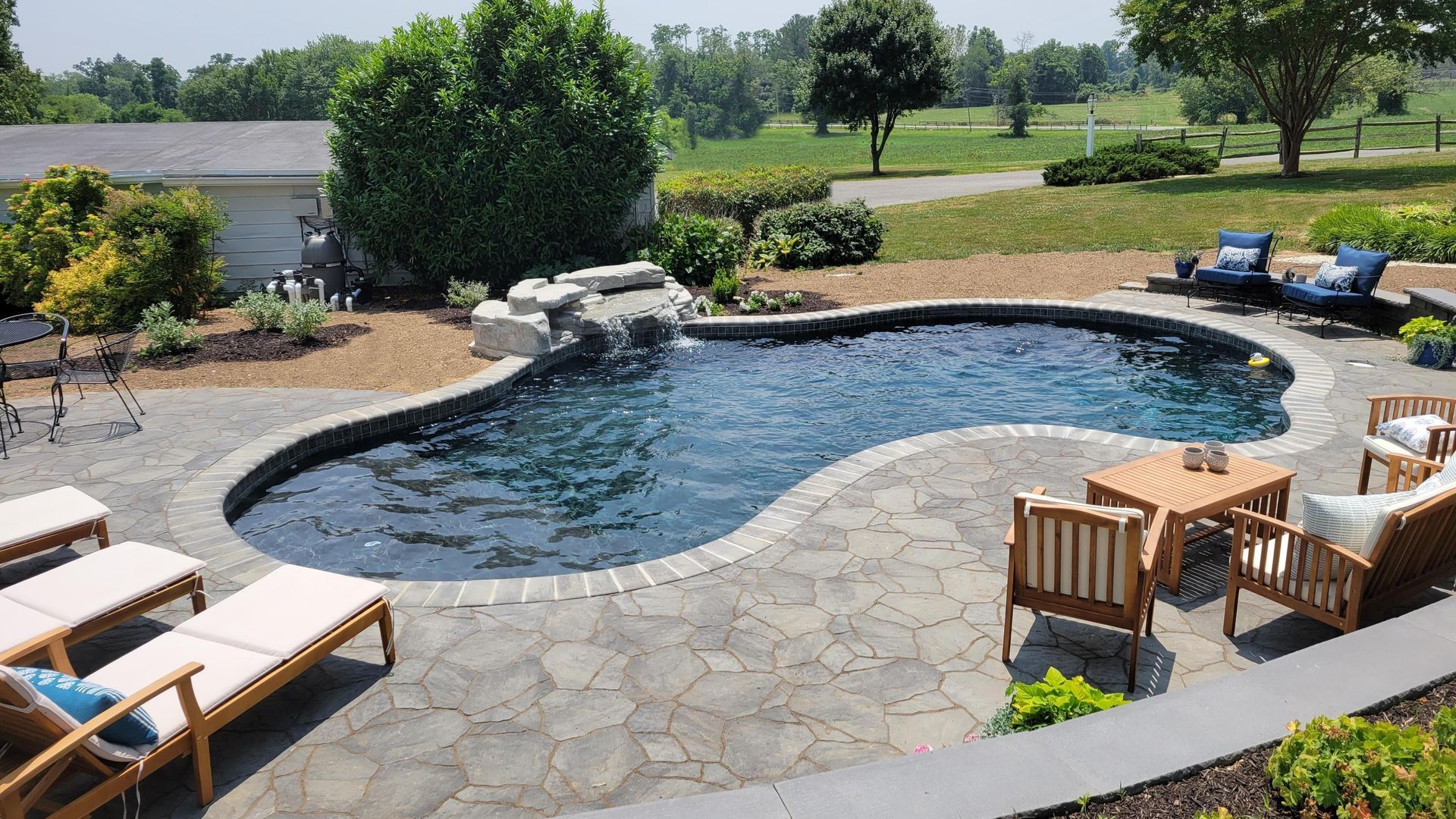 A large swimming pool is surrounded by chairs and a patio.