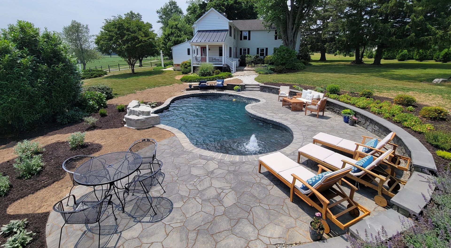 A large swimming pool is in the backyard of a house