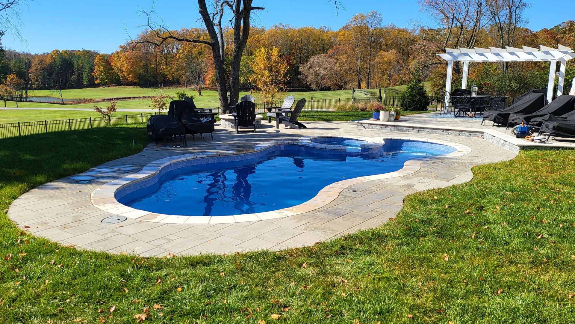 There is a large swimming pool in the middle of a lush green field.