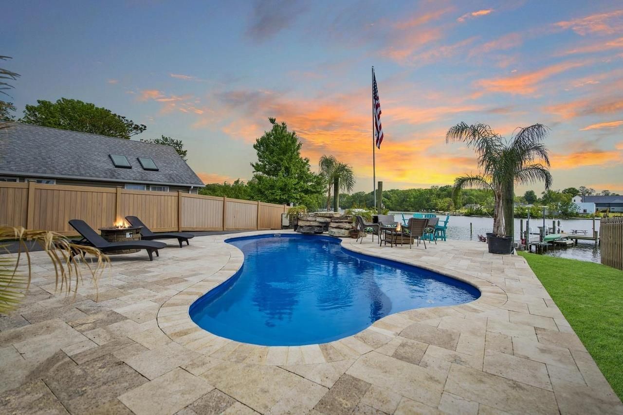 There is a large swimming pool in the backyard of a house.