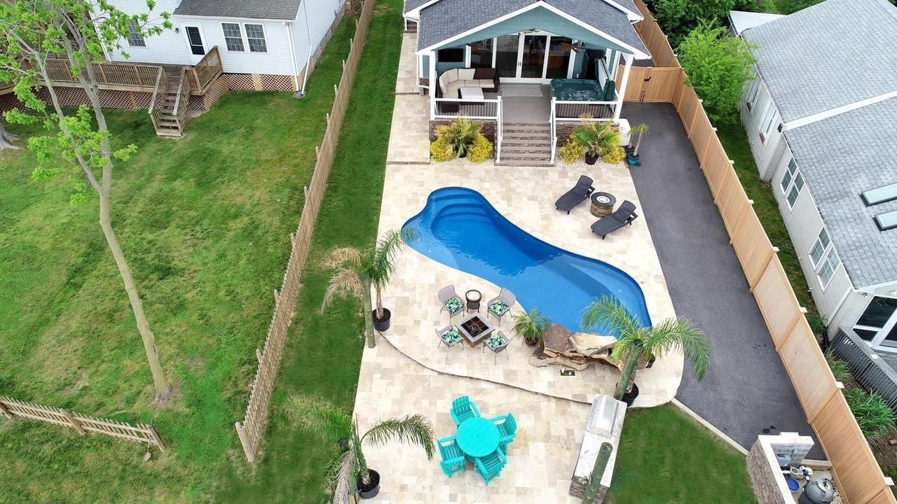 An aerial view of a house with a large swimming pool in the backyard.