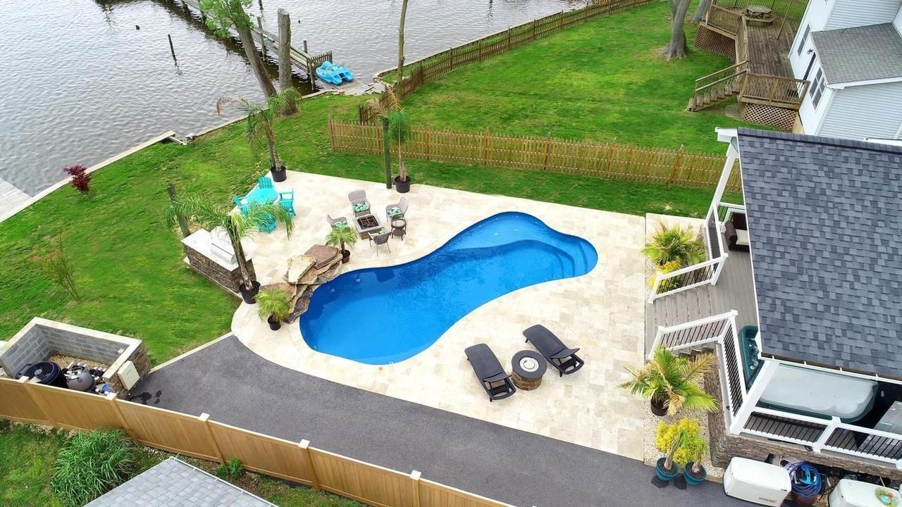 An aerial view of a house with a large swimming pool in the backyard.