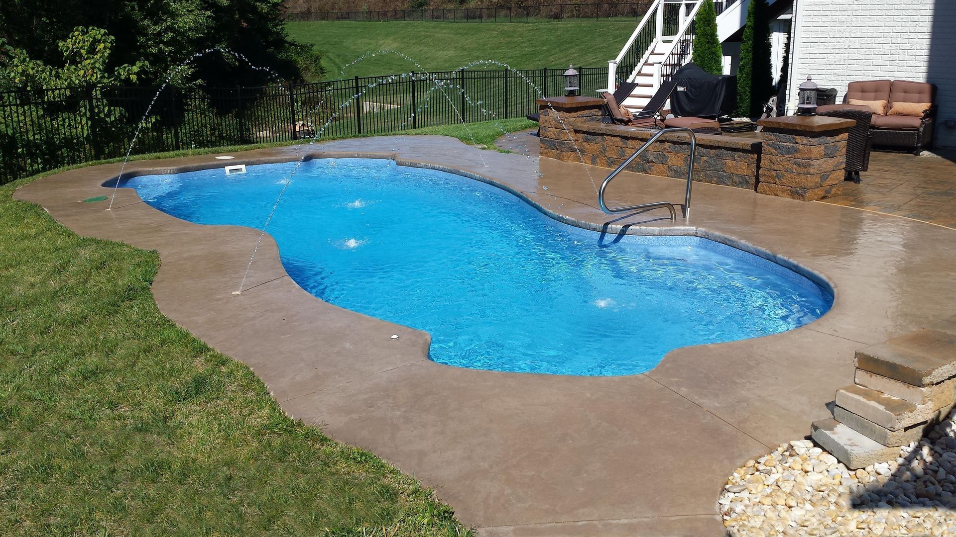 A large swimming pool is in the backyard of a house.