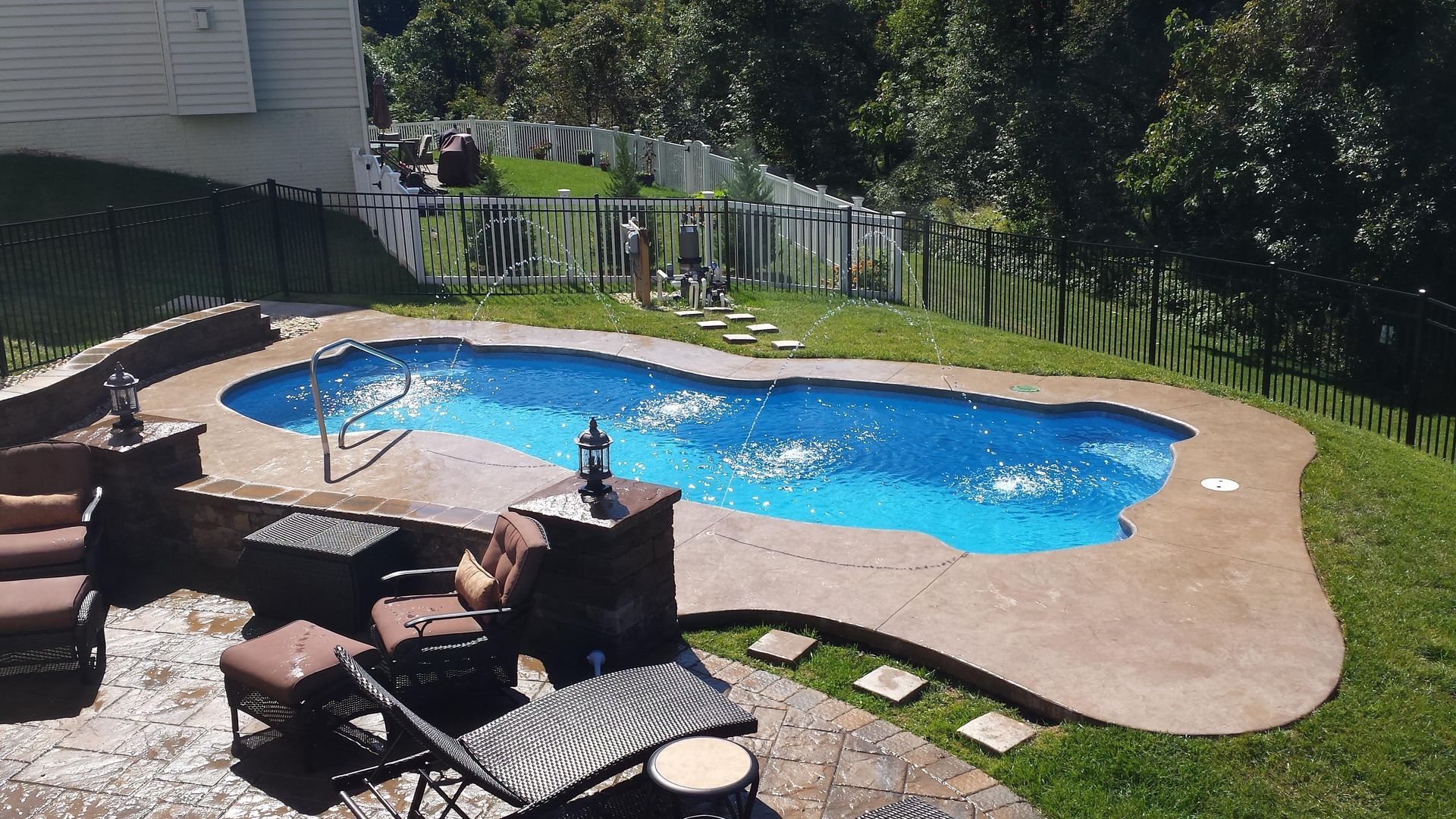 A large swimming pool is in the backyard of a house