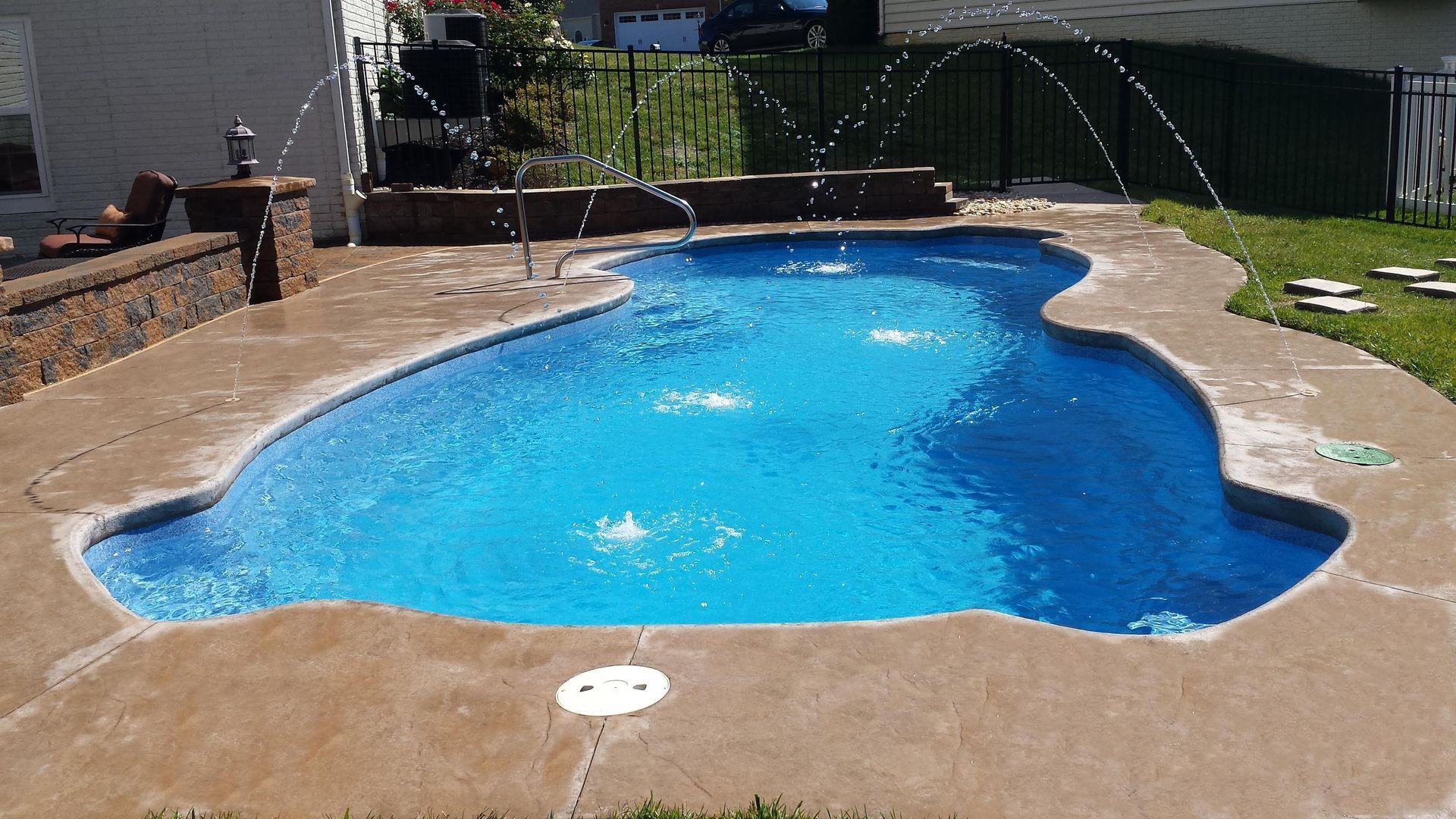 A large swimming pool with a fountain in the backyard
