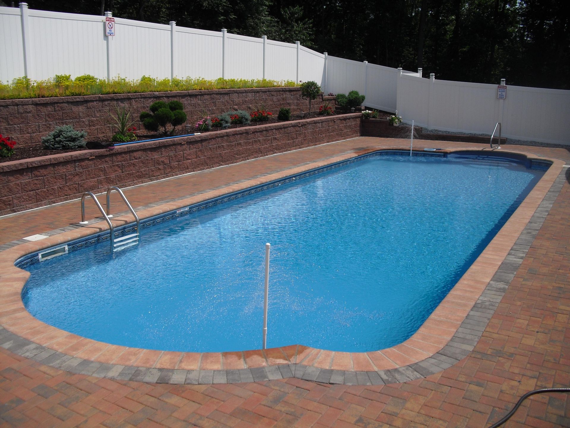 A large swimming pool is surrounded by a white fence
