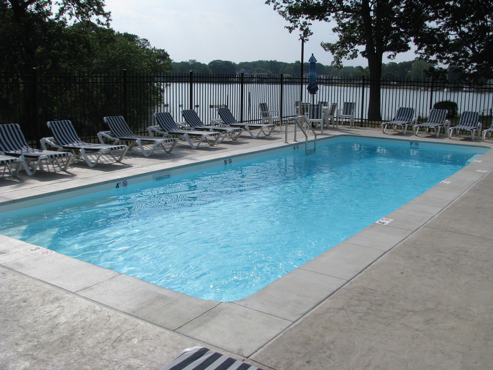 A large swimming pool surrounded by chairs and a fence