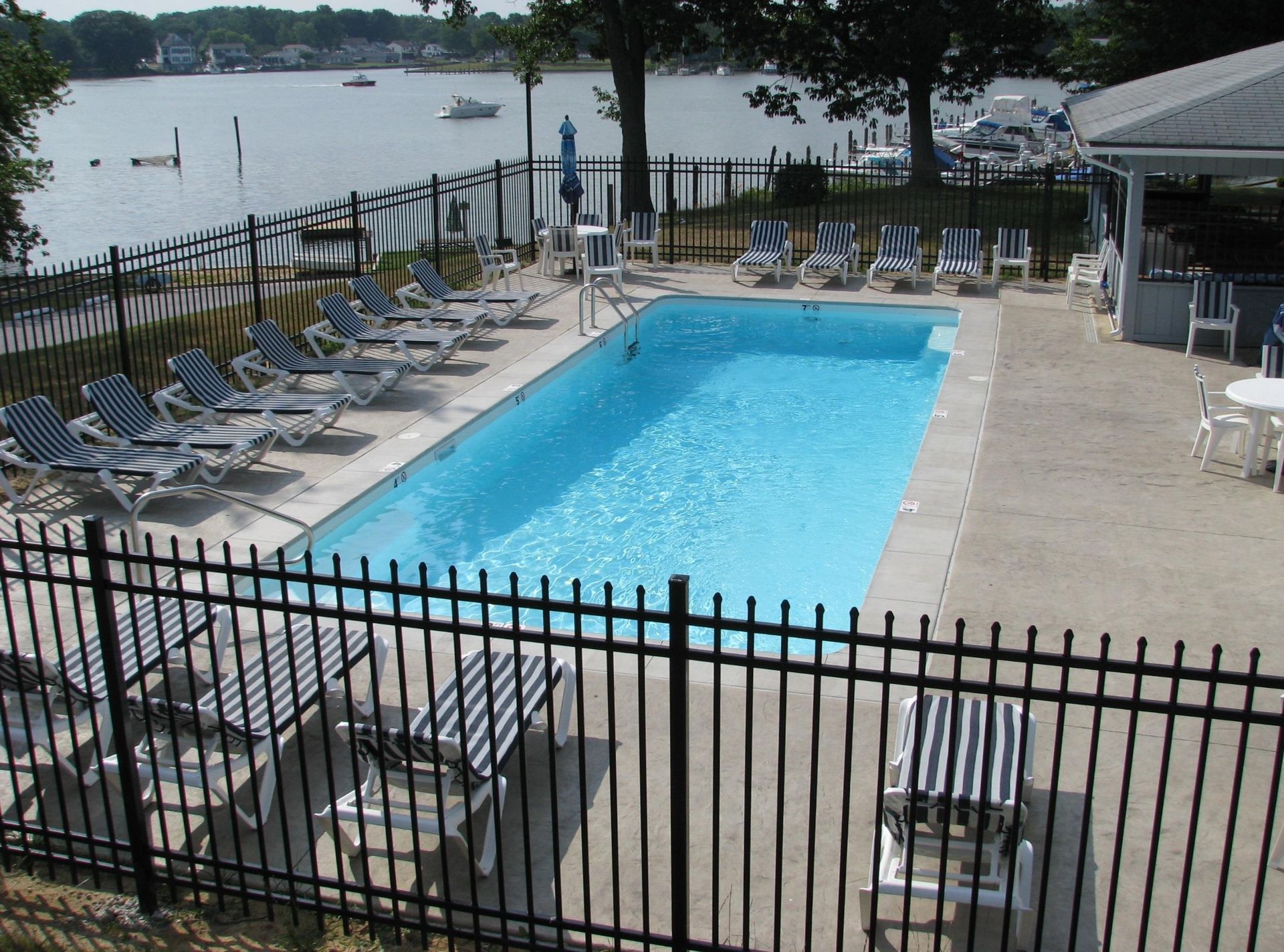 A large swimming pool surrounded by chairs and a fence