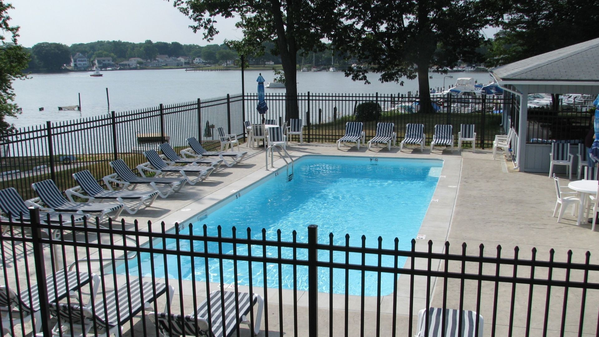 A large swimming pool surrounded by chairs and a fence