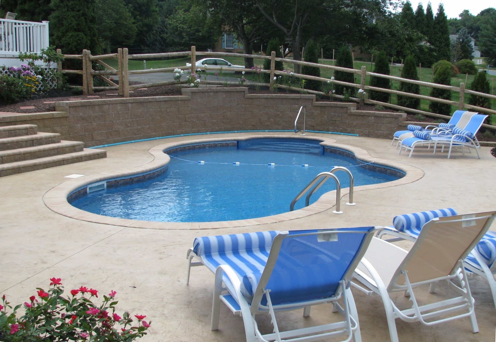 A swimming pool surrounded by chairs and a wooden fence