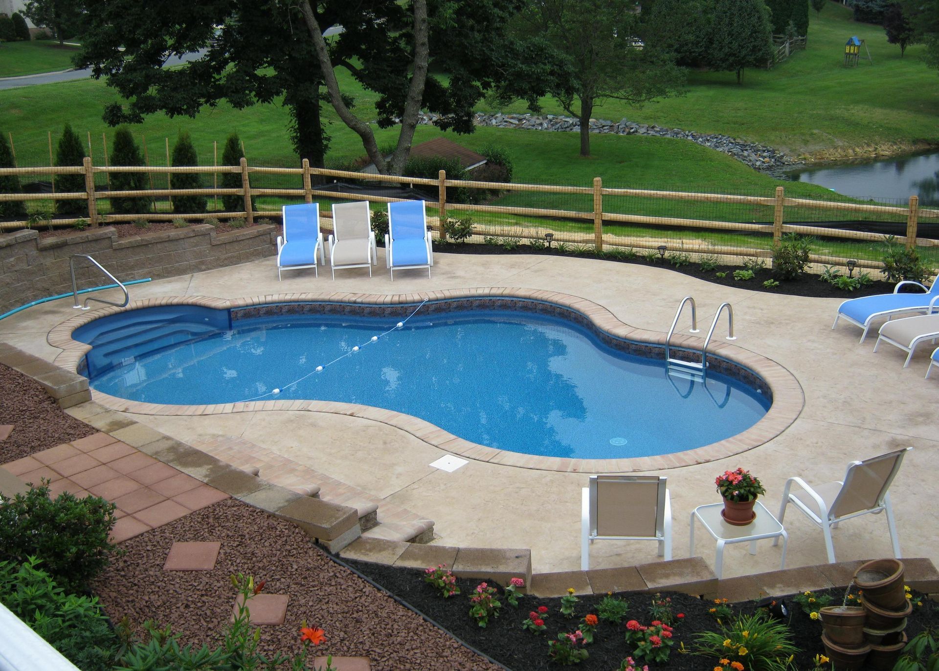 A large swimming pool surrounded by chairs and a wooden fence