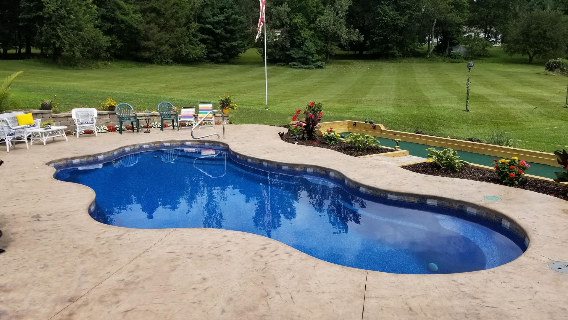A large swimming pool is in the middle of a lush green field.