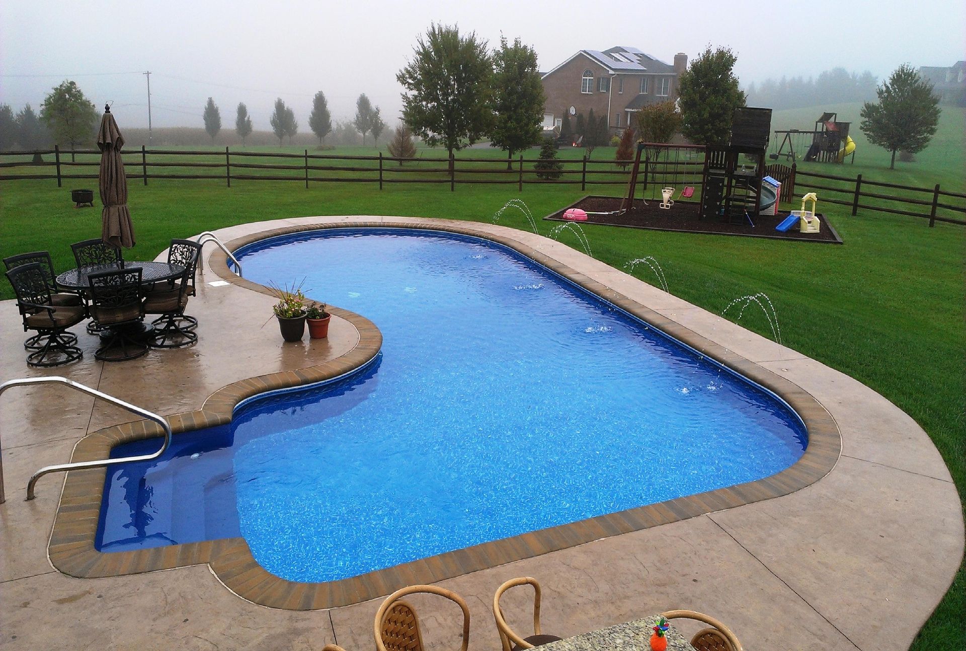 A large swimming pool in the middle of a lush green field