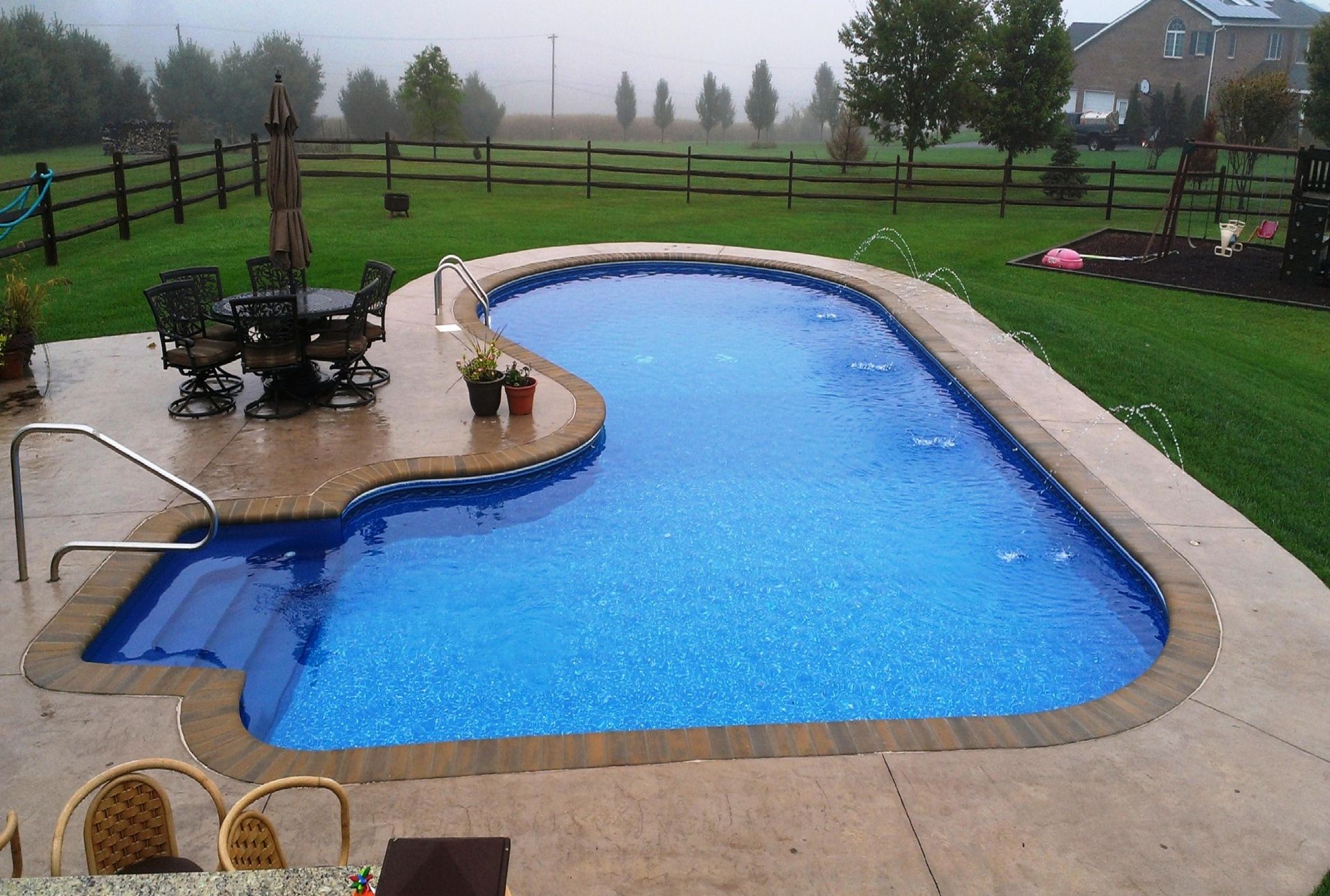 A large swimming pool with a table and chairs around it
