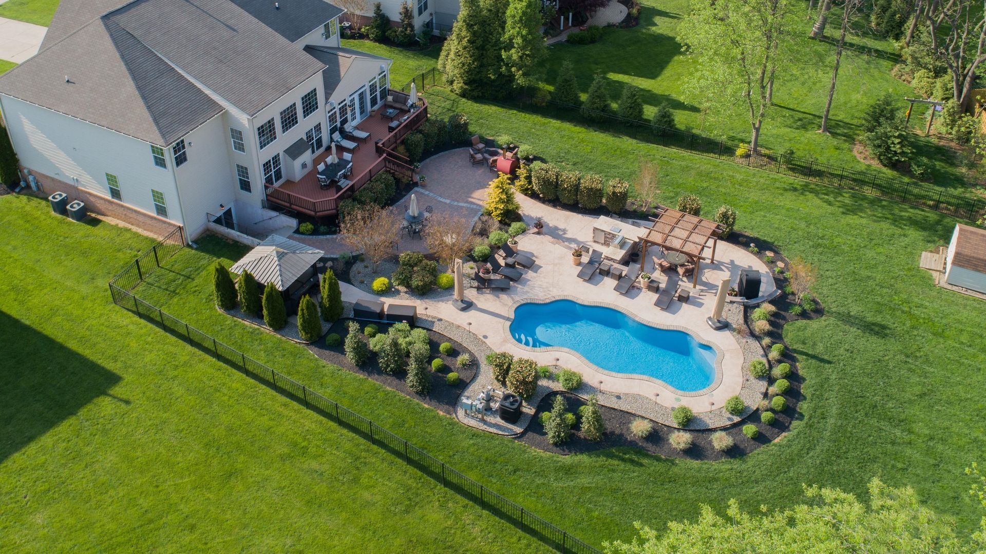 An aerial view of a house with a large swimming pool in the backyard.