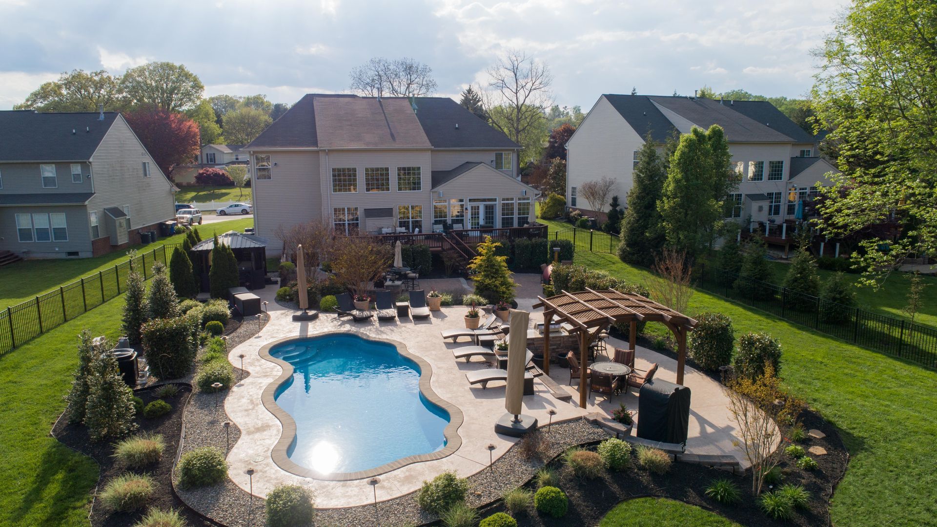 An aerial view of a large swimming pool in the backyard of a house.