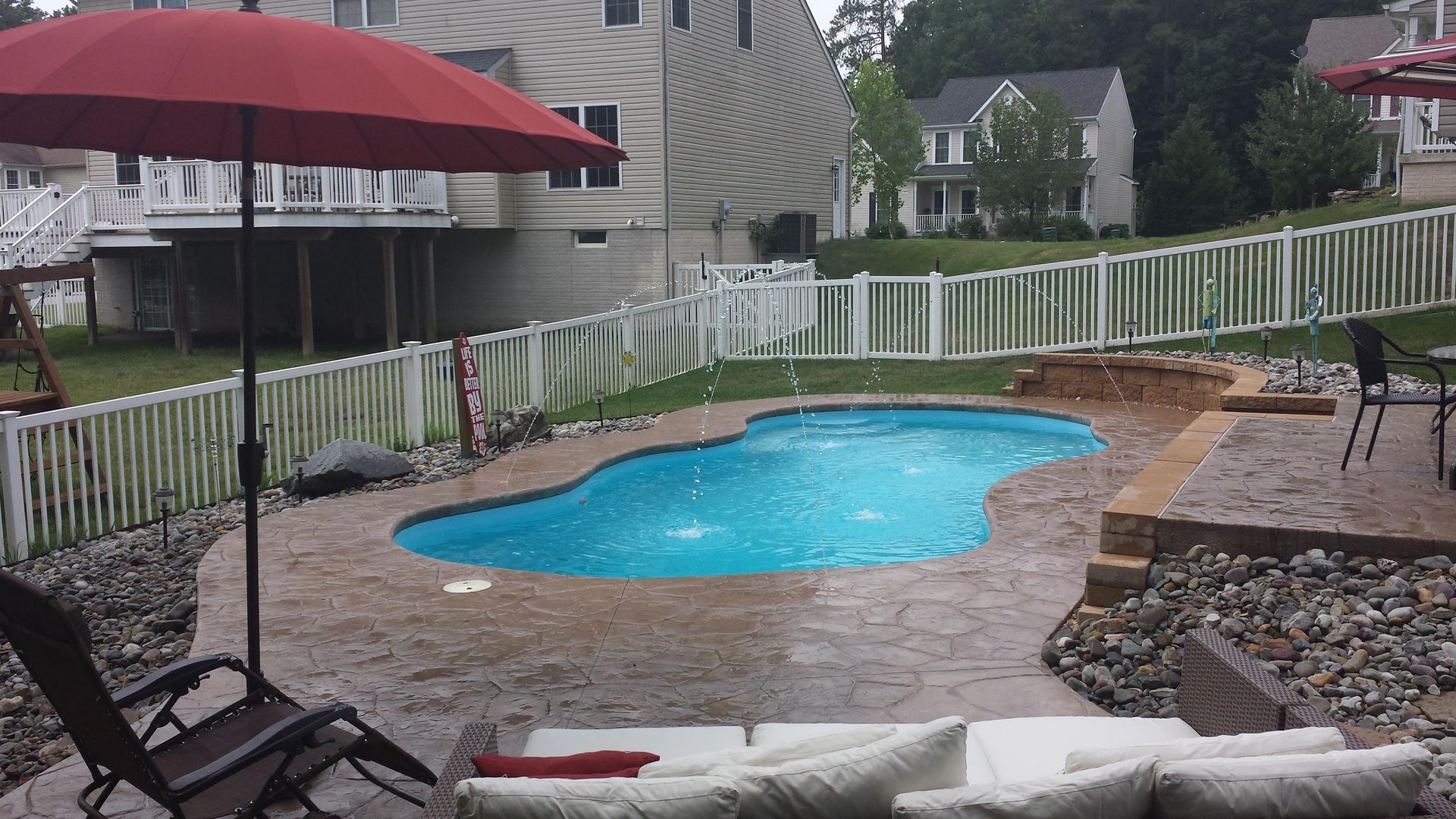 A large swimming pool with a red umbrella in front of it