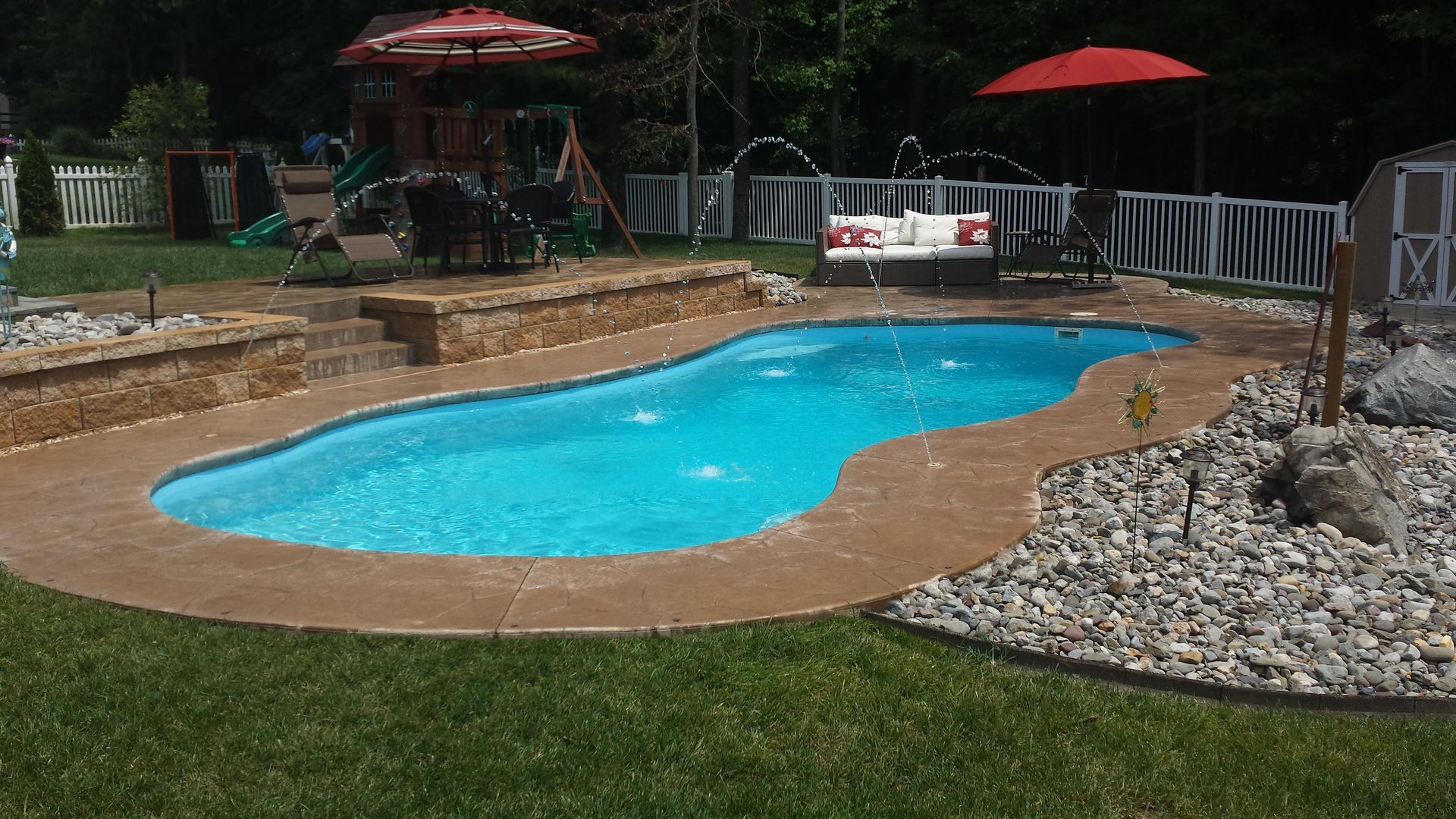 A large swimming pool in a backyard with a red umbrella