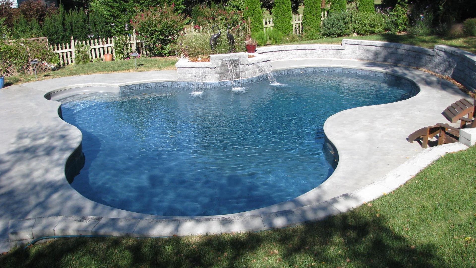 A large swimming pool with a waterfall in the backyard