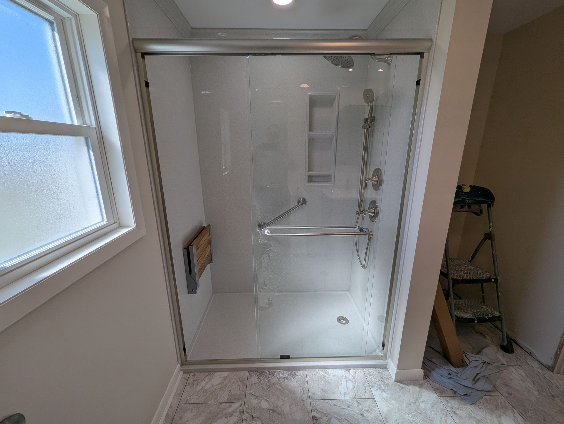 A bathroom with a sliding glass shower door and a window.