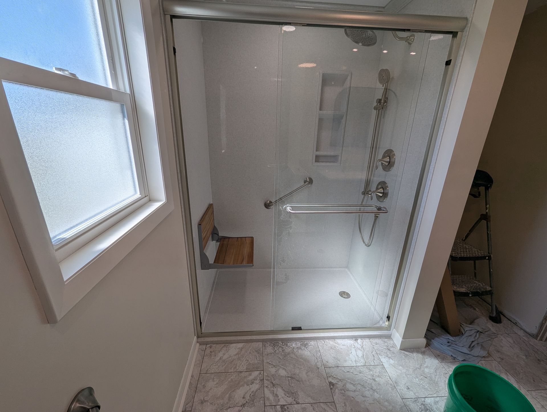 A bathroom with a sliding glass shower door and a window.