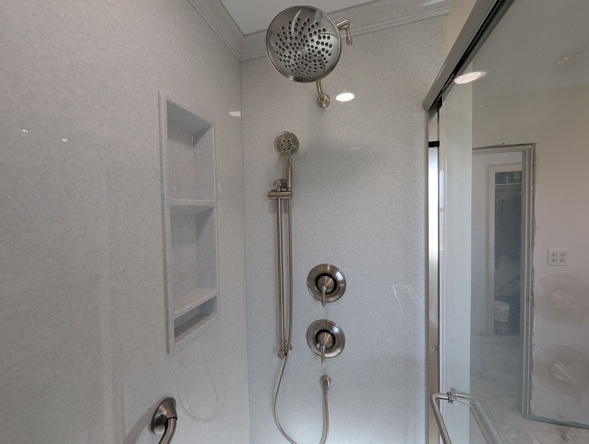 A shower with a sliding glass door and a shower head.