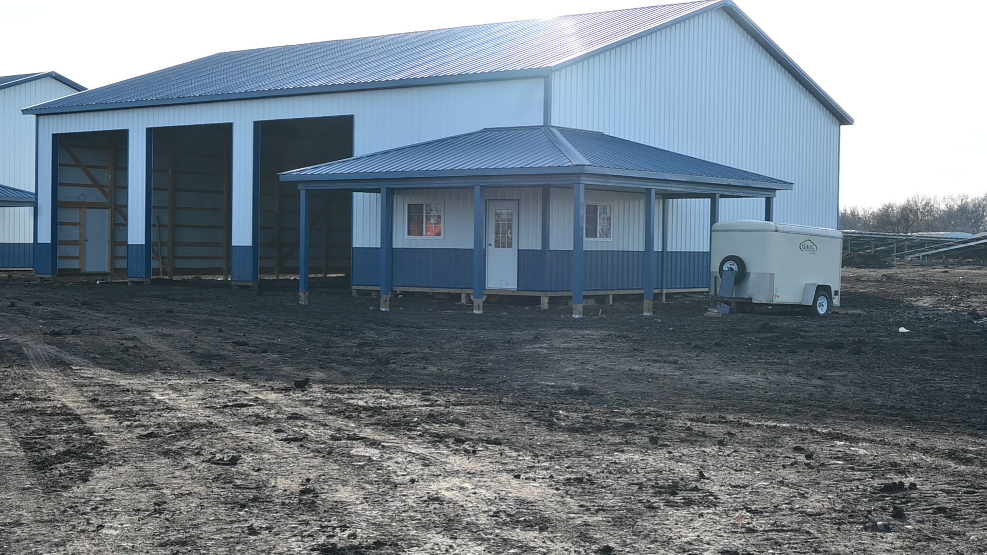 A white building with a blue porch and a trailer in front of it