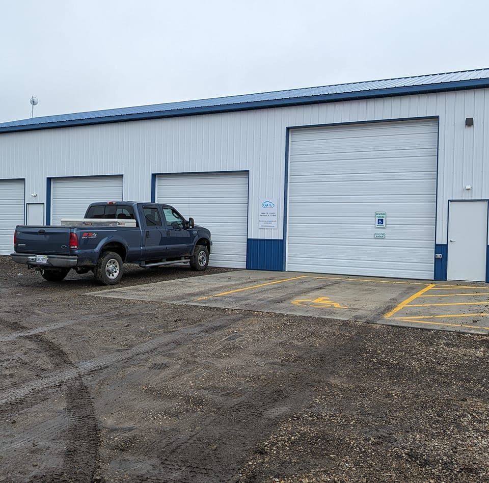 A blue truck is parked in front of a garage