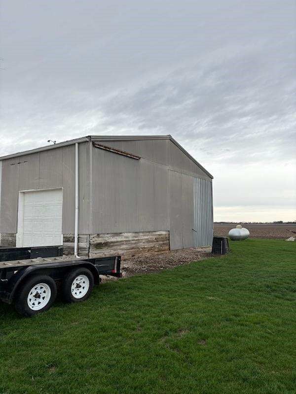 A trailer is parked in front of a building in a grassy field.