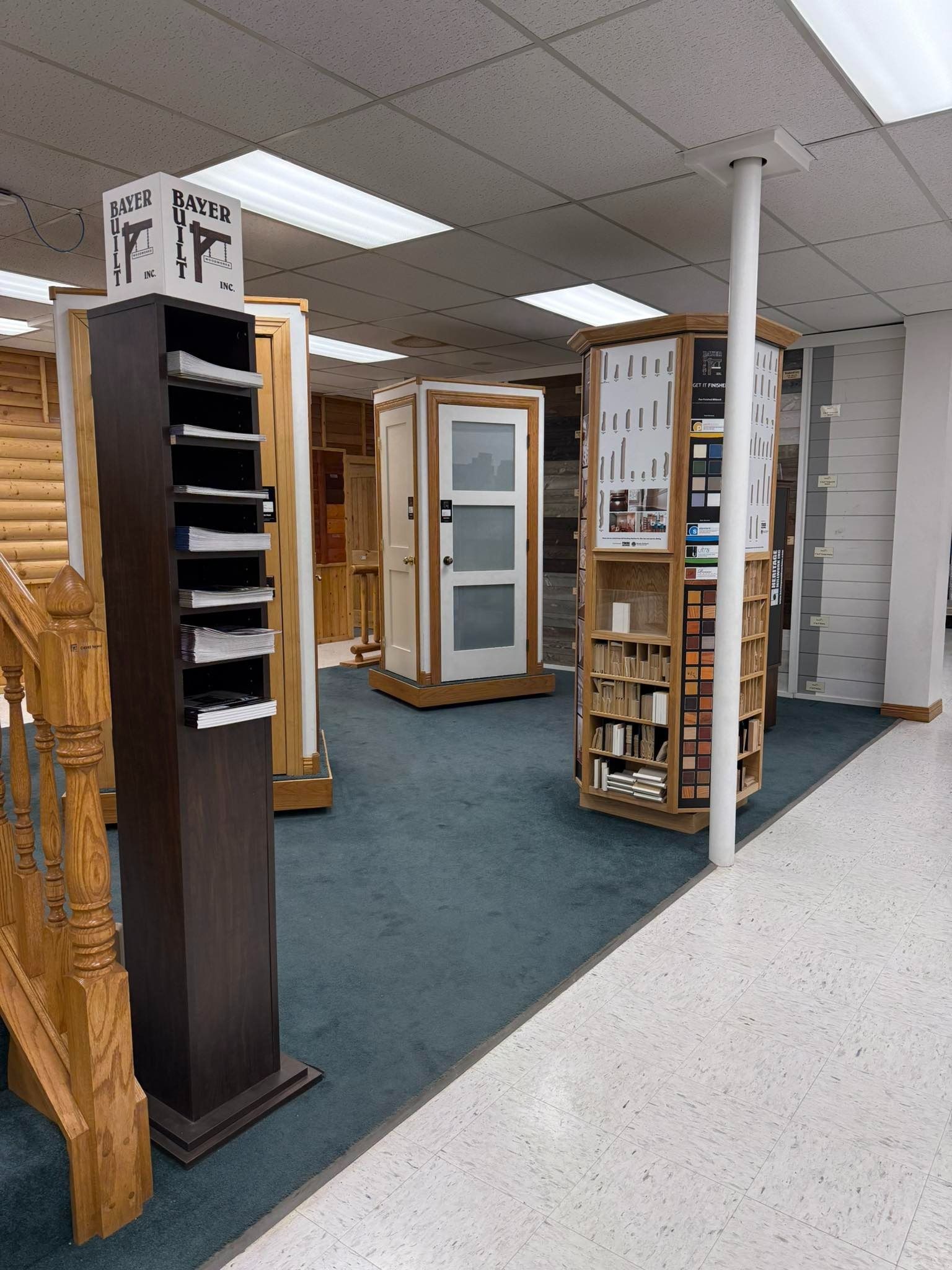 Showroom with wood display racks, shelving units, and a carpeted floor under fluorescent lights