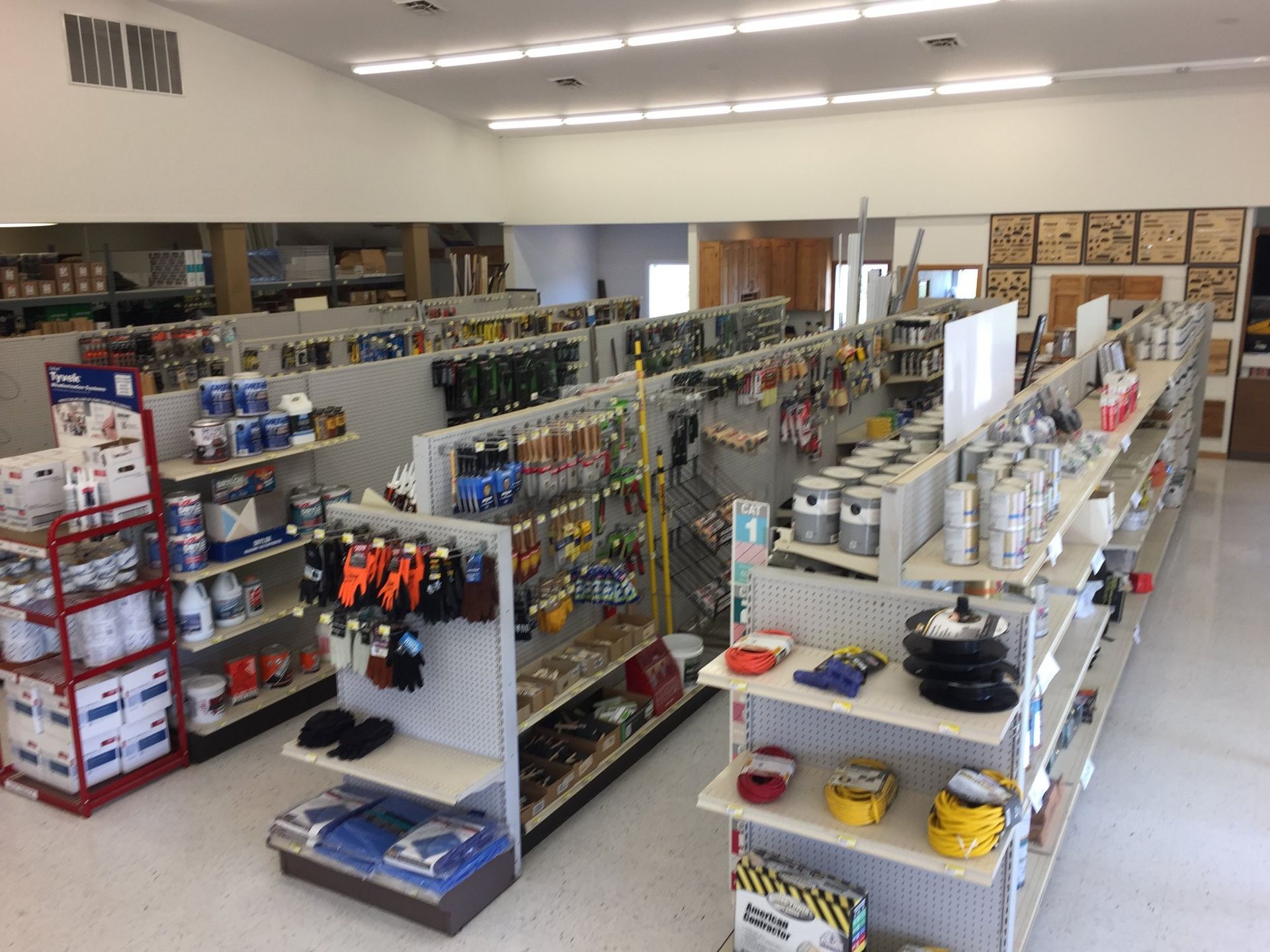Interior of a hardware store aisle with shelves of tools, paint cans, and supplies