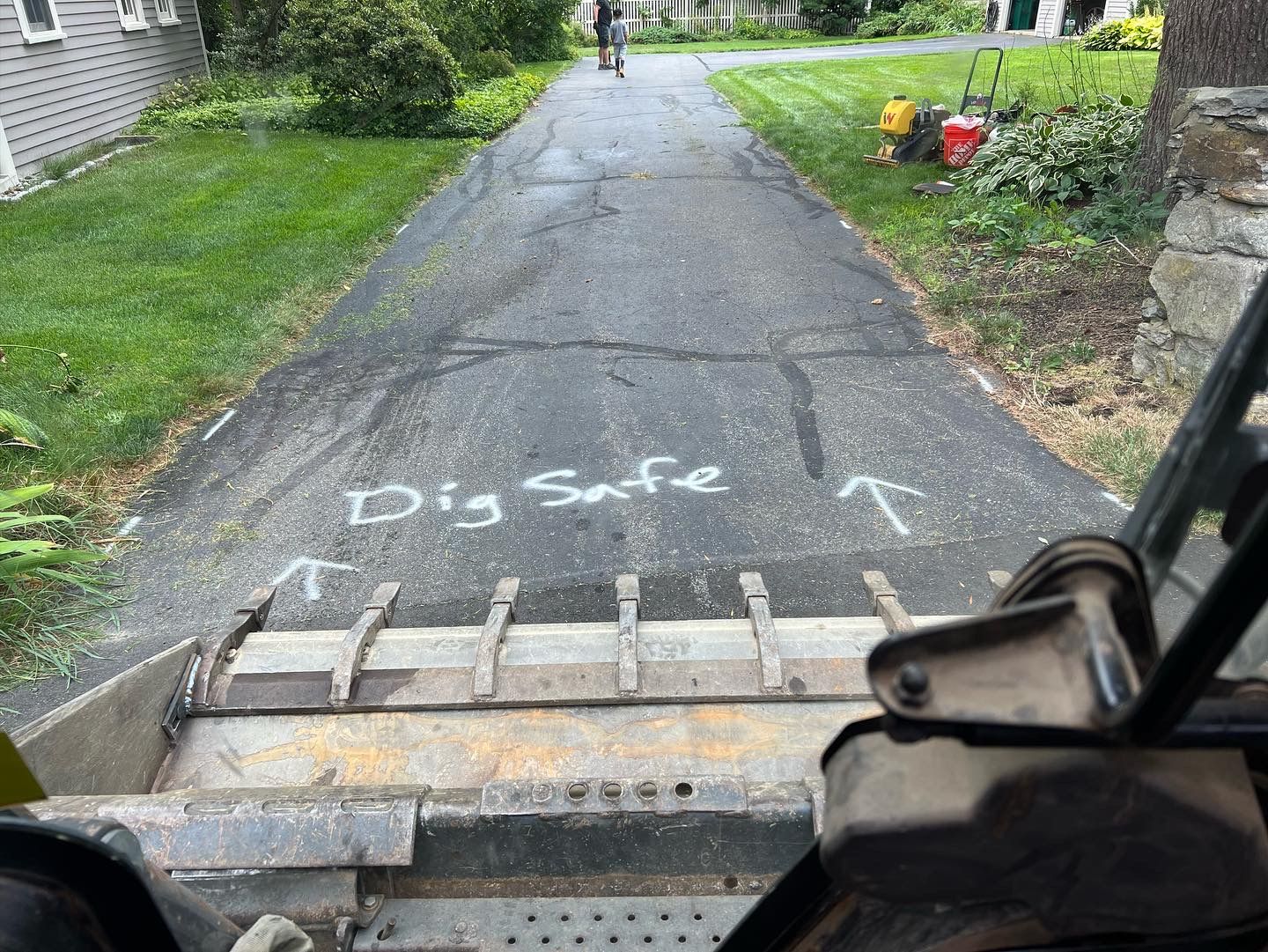 View from a skid steer bucket on a cracked driveway. 
