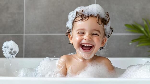 Smiling child in a bubble-filled bathtub, with soap suds on the hair and a bathroom backdrop