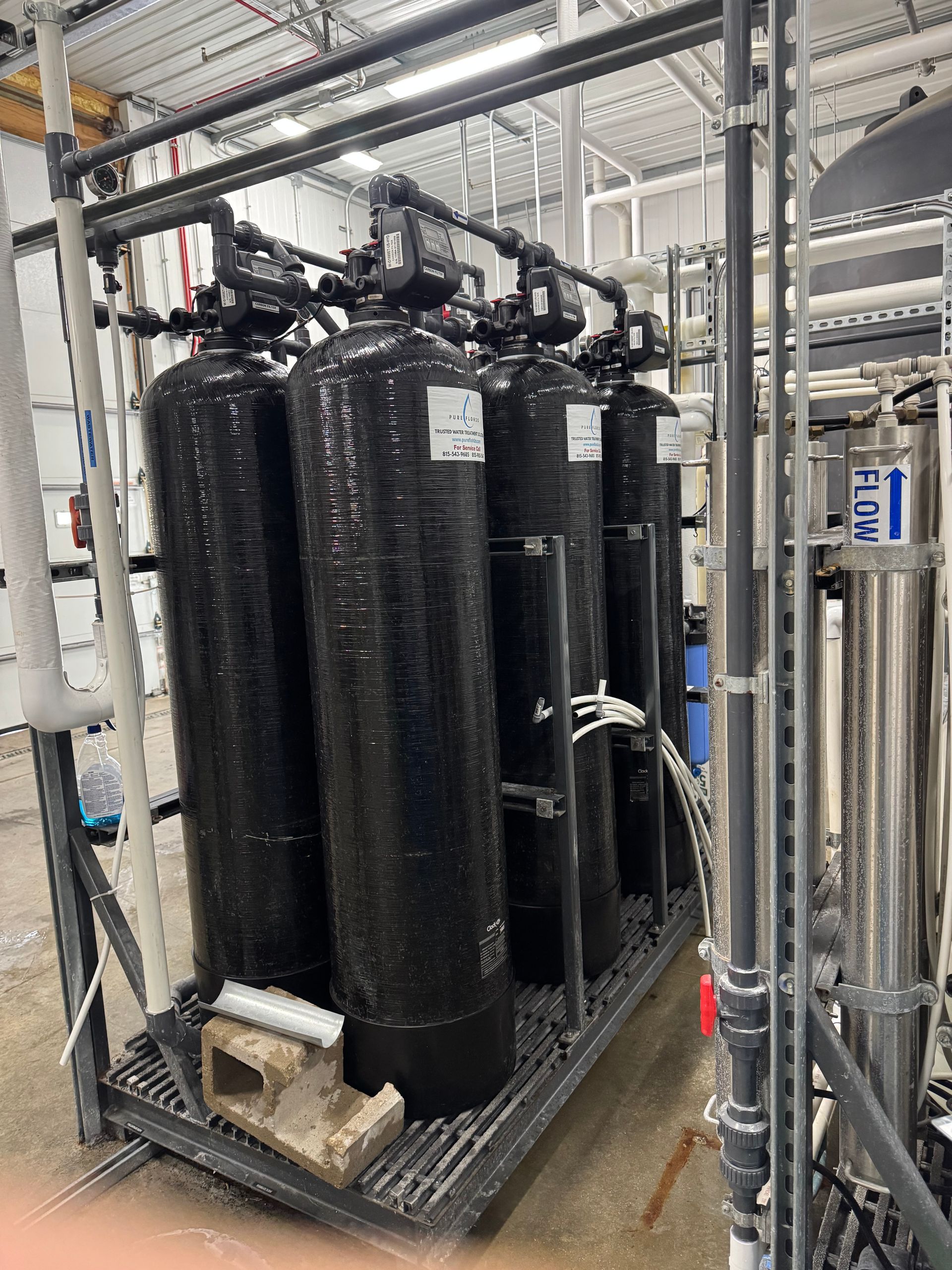 Industrial water treatment tanks with pipes and gauges inside a mechanical room