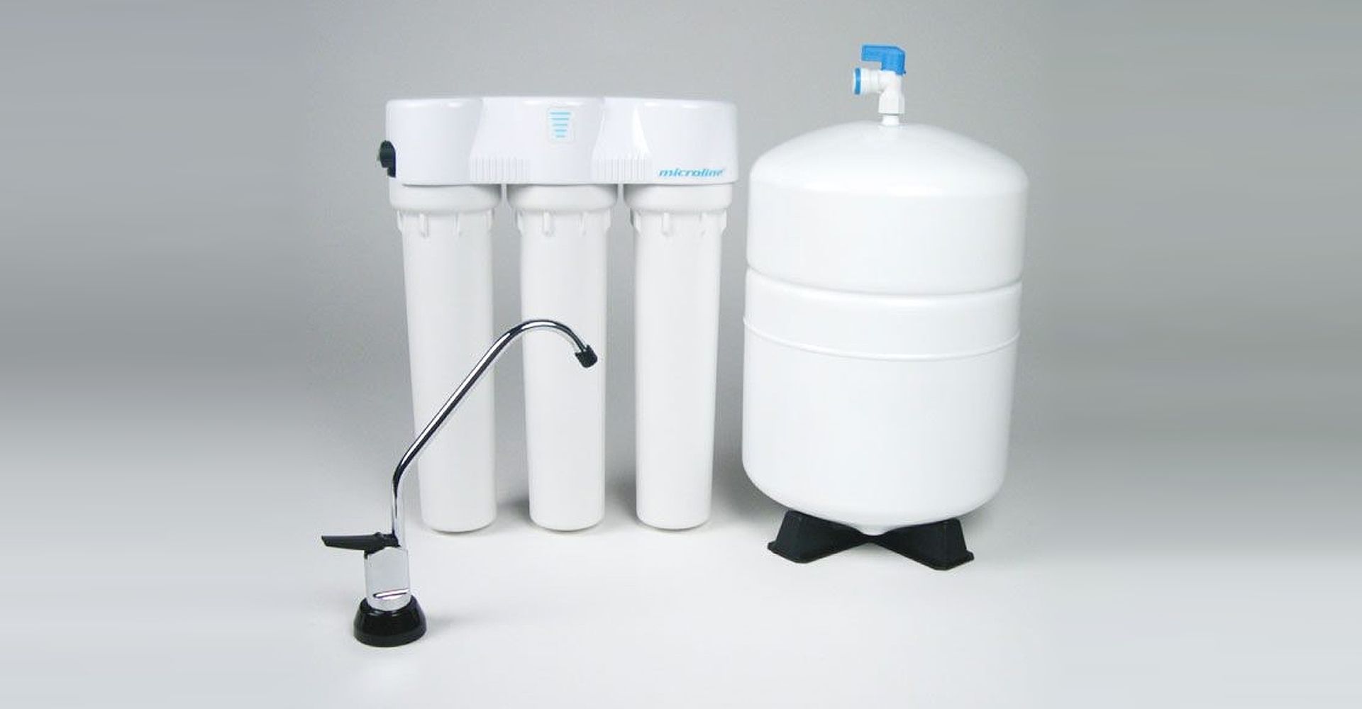 Chrome faucet with running water in a white bathroom sink. Soap dispenser and towel visible.