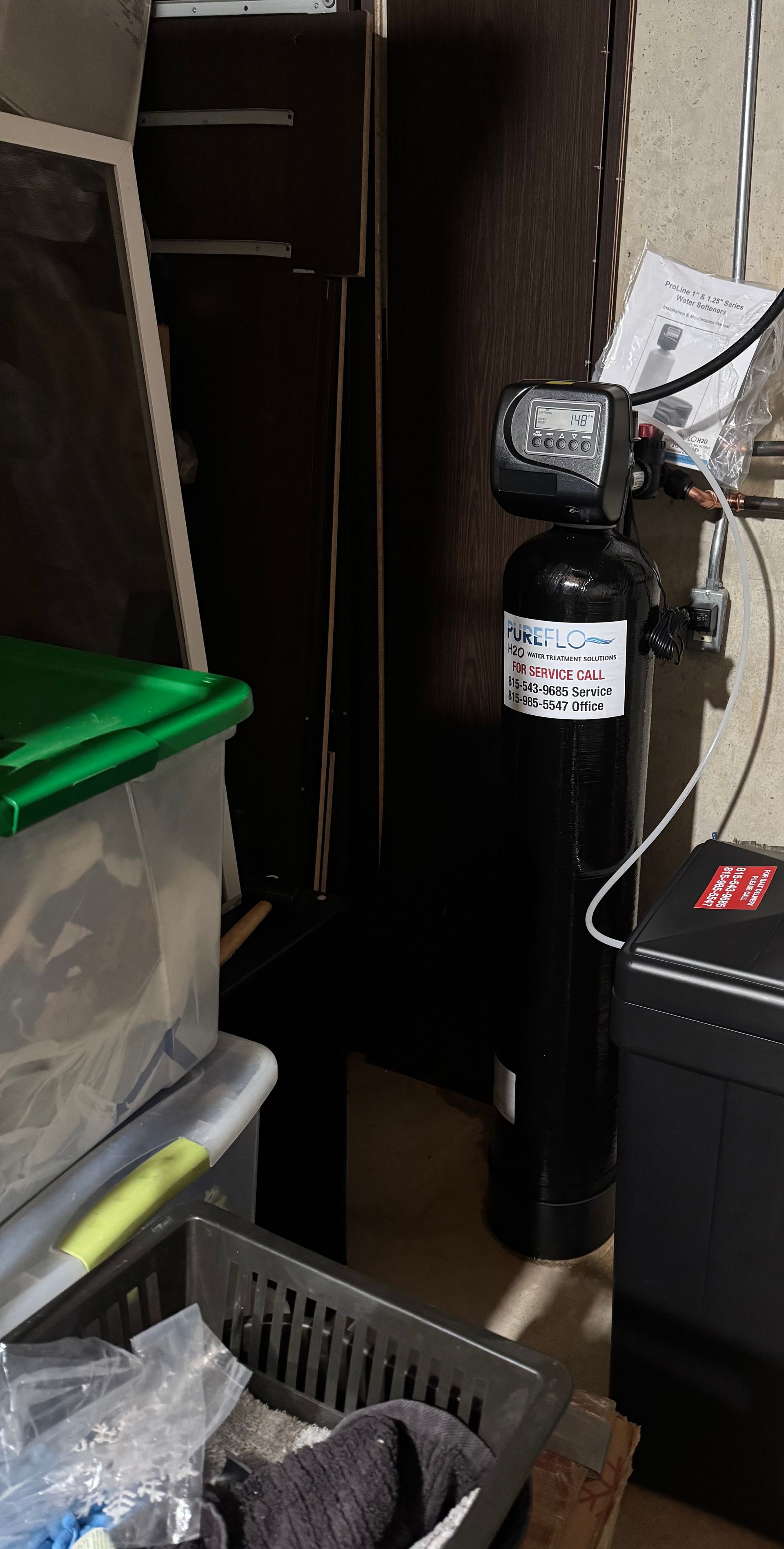 Water softener system in a storage area. Black tank with digital display.