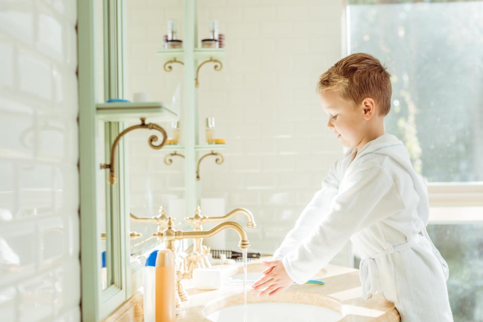 Child washing hand in bathroom