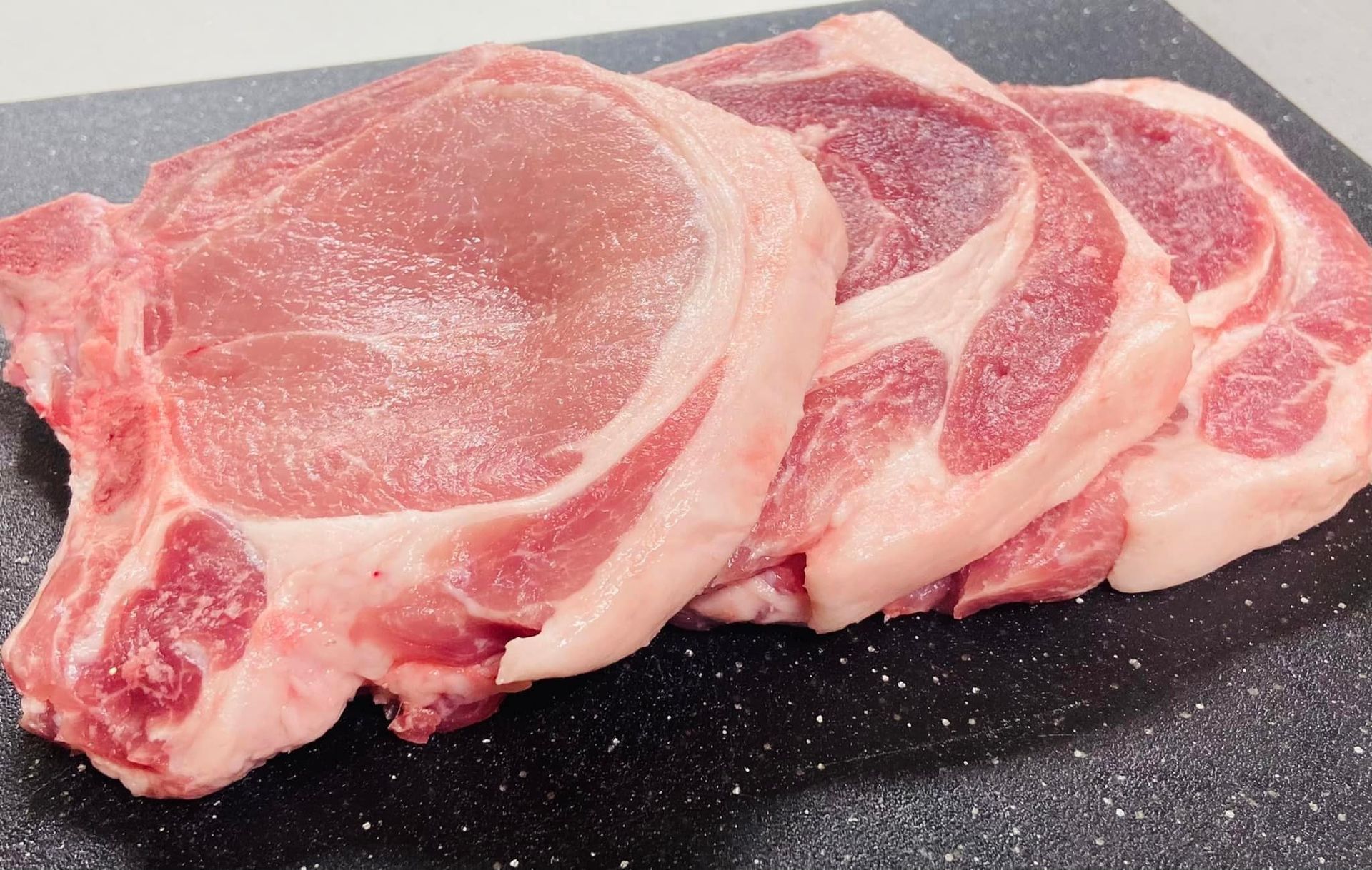 A pile of raw pork chops on a cutting board