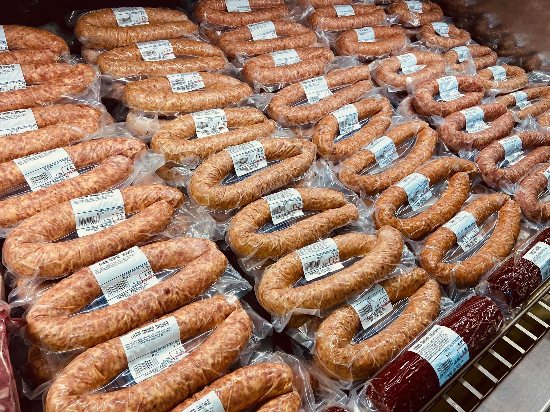 A bunch of sausages are sitting on top of each other in a refrigerator.