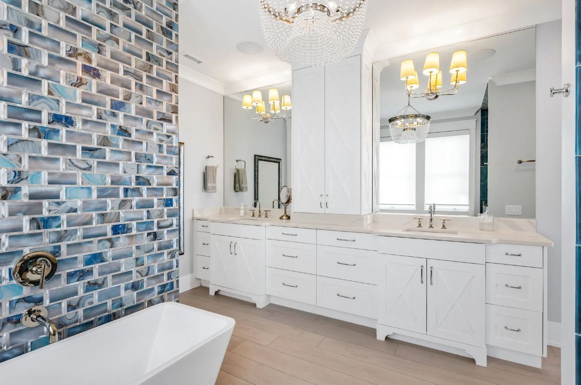 A bathroom with two sinks, a tub, a mirror and a chandelier.