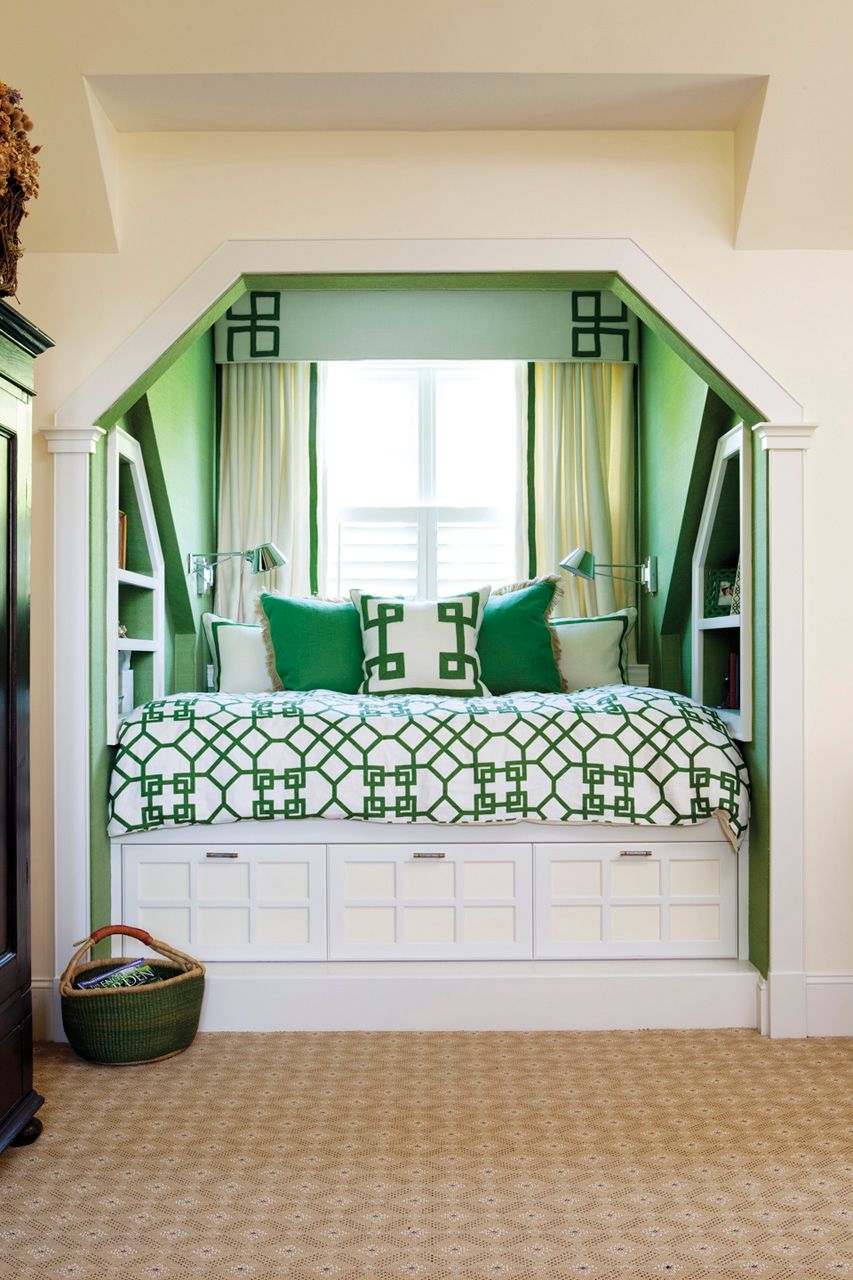 A bed in a window seat with green pillows