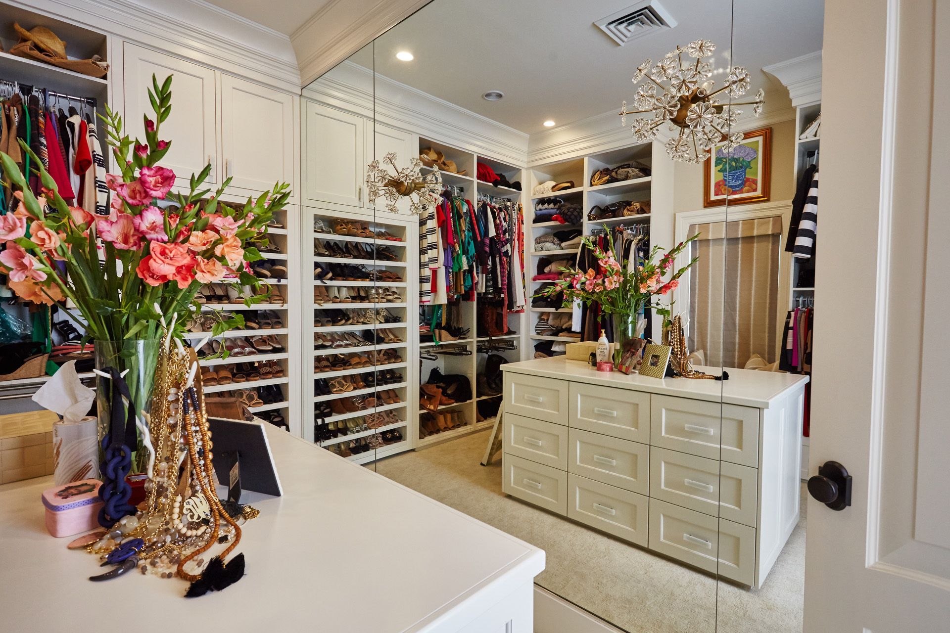 A walk in closet filled with lots of clothes and shoes.