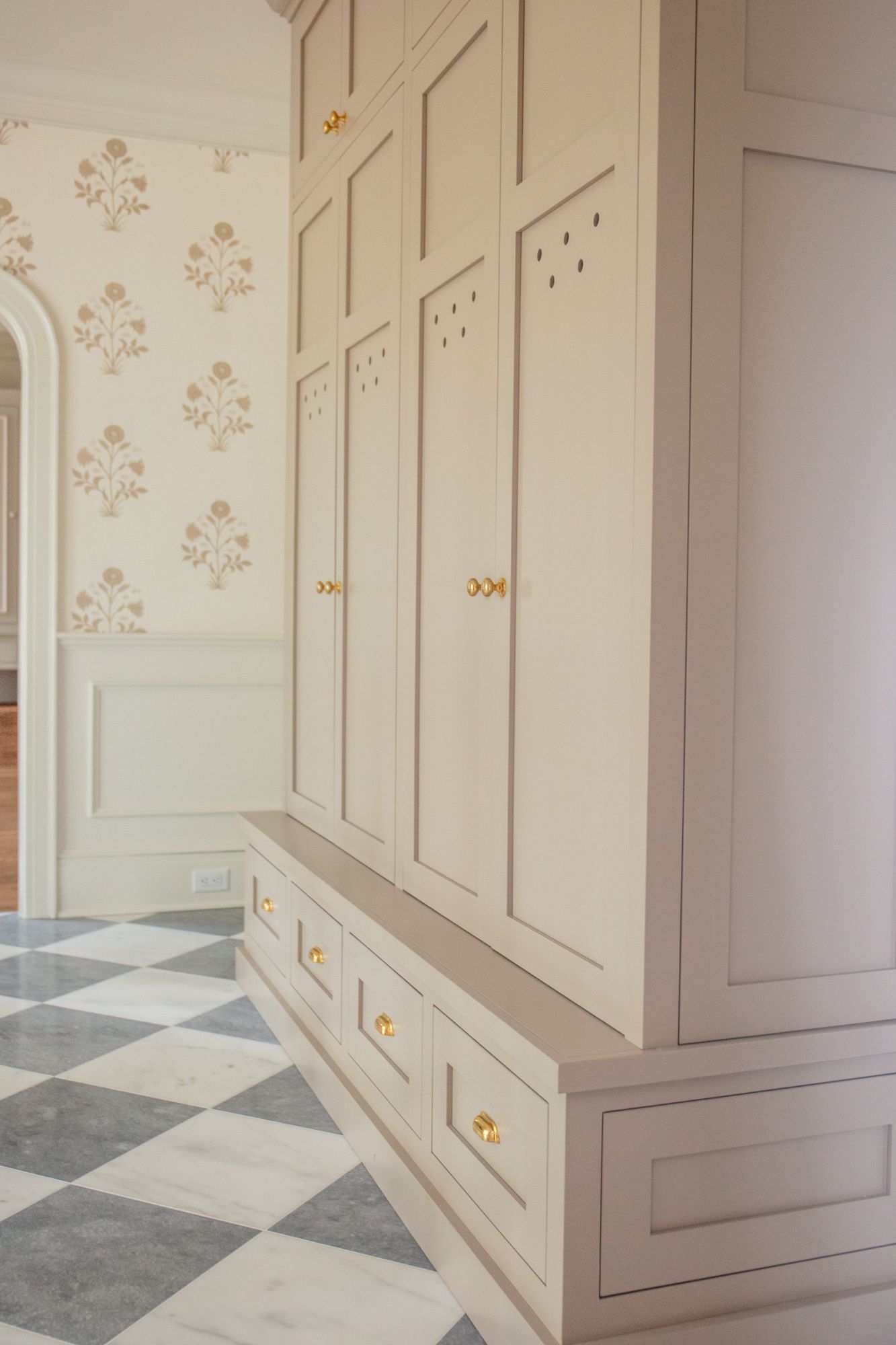 A hallway with a checkered floor and white cabinets.