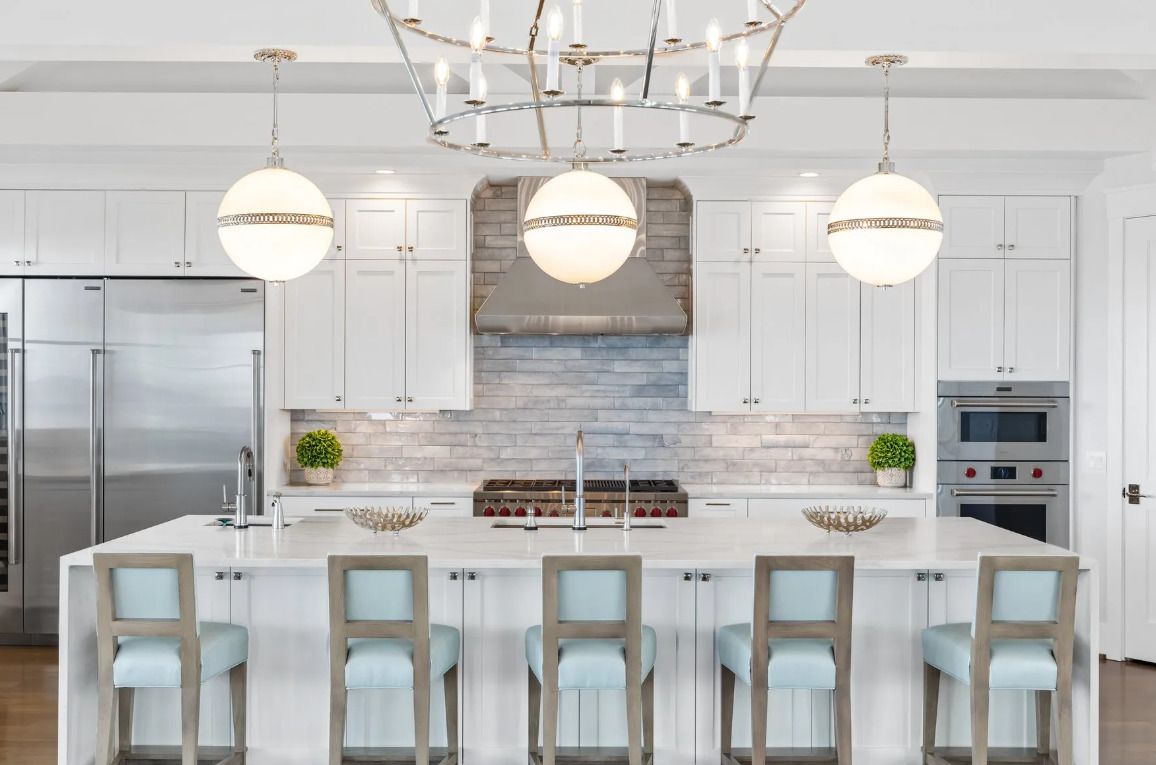 A kitchen with white cabinets, stainless steel appliances, a large island, and a chandelier.