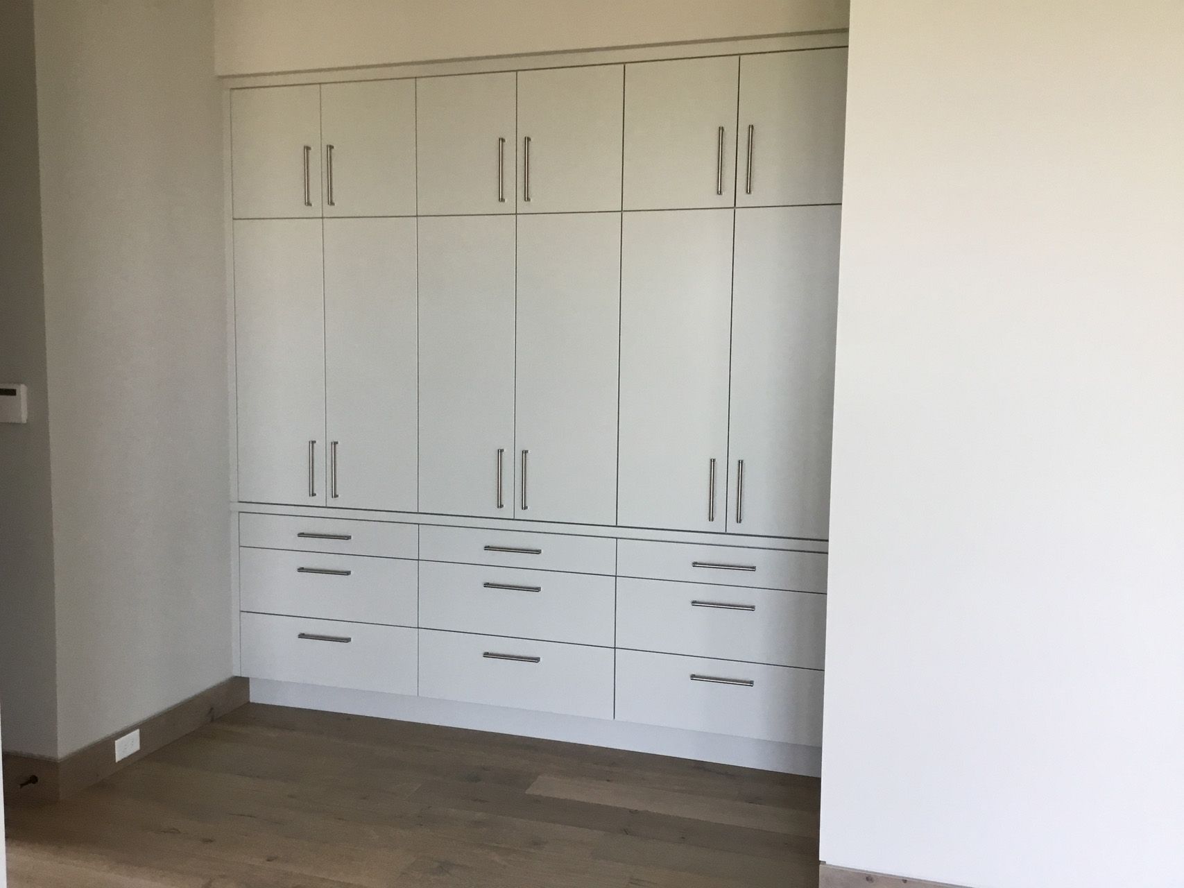 A room with a lot of white cabinets and drawers