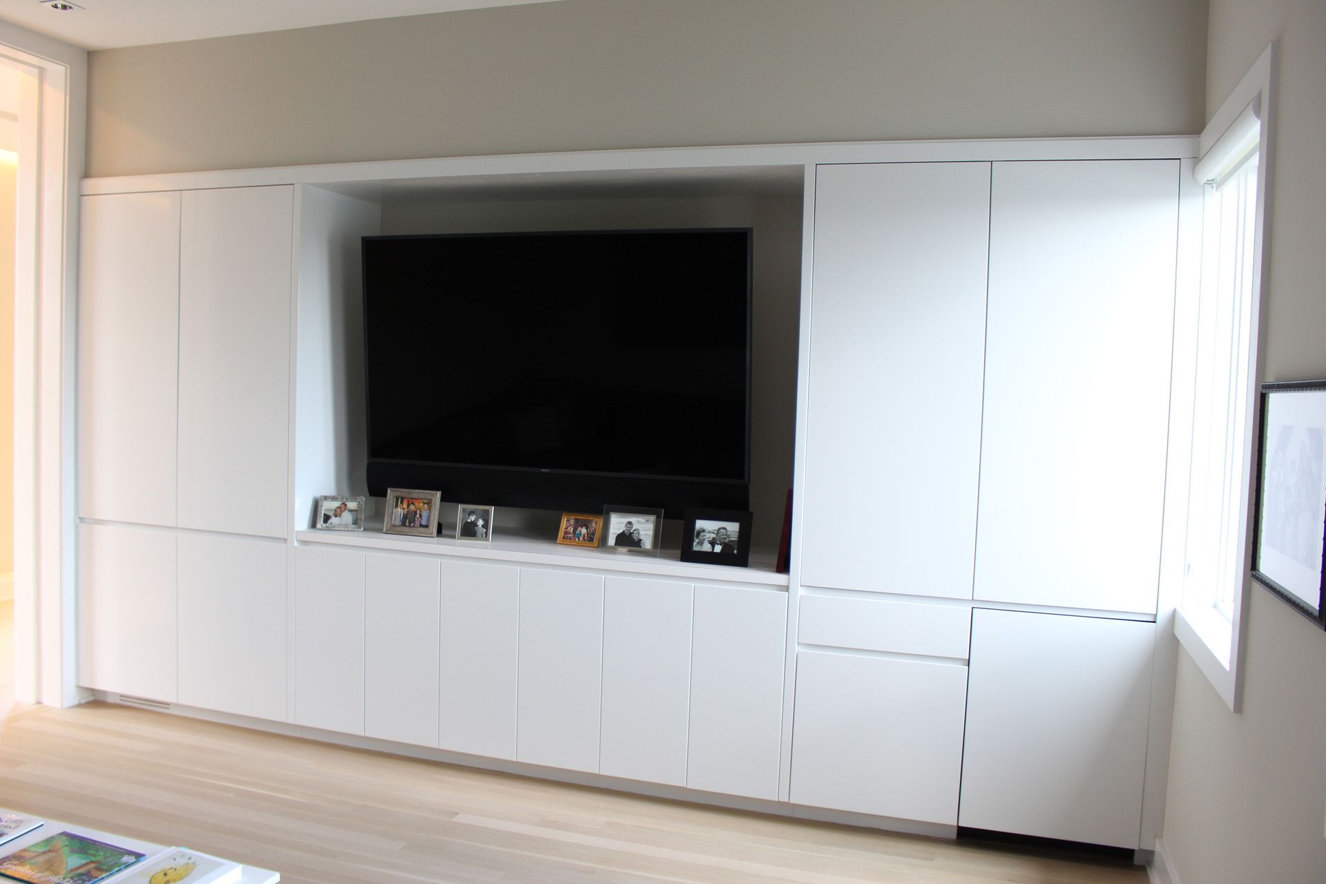 A living room with white cabinets and a flat screen tv.