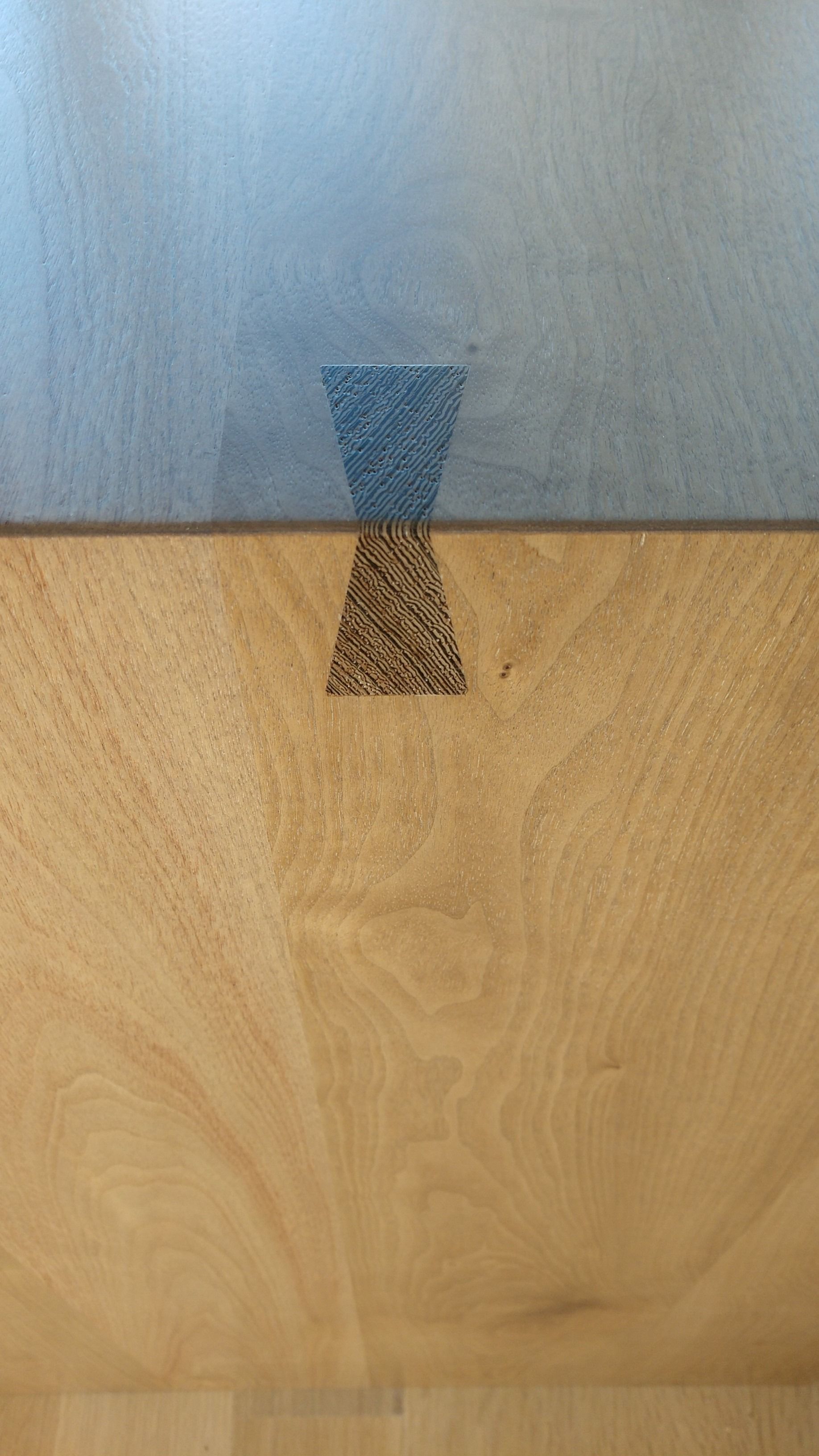 A close-up of a wooden surface with a dark butterfly-shaped patch, used to reinforce a joint.